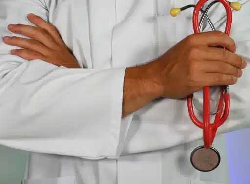 Male doctor in white lab coat crosses his arms with a stethoscope in hand