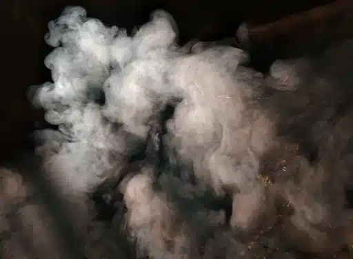 White smoke rises from an unknown source on a black background