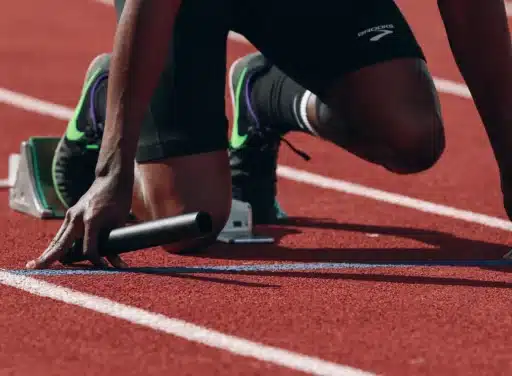 African-American runner kneels at the starting gate of a relay race