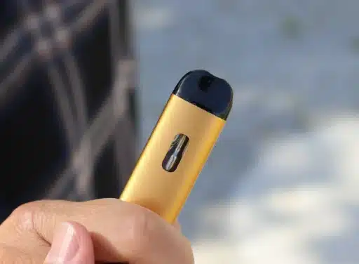 A gold vape device held by a hand