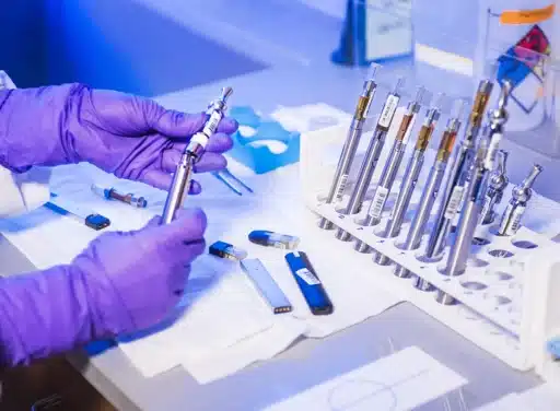 Gloved hands of a Centers for Disease Control and Prevention (CDC) laboratory technician working with electronic cigarettes, referred to as e-cigarettes, or e-cigs, and vaping pens, while inside a laboratory environment