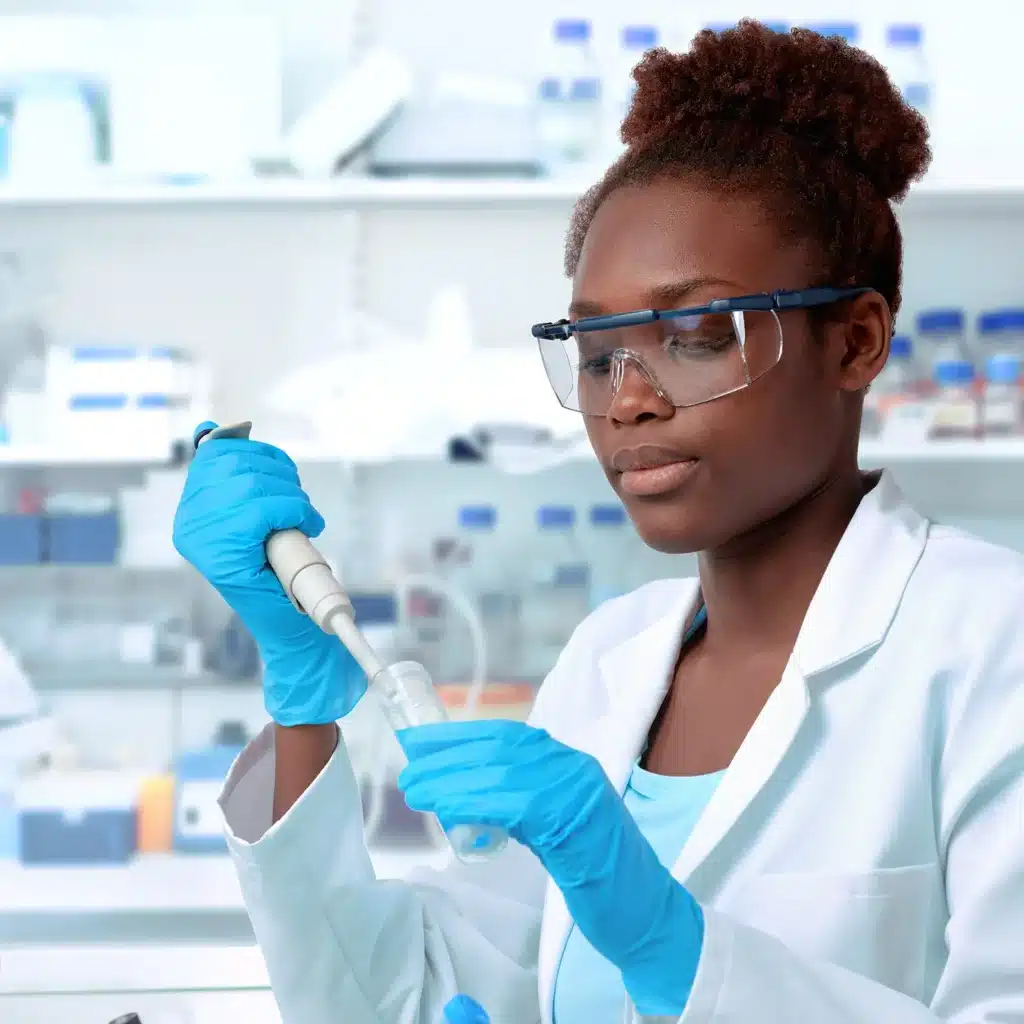 African-American scientist or graduate student in lab coat and protective wear works in modern laboratory